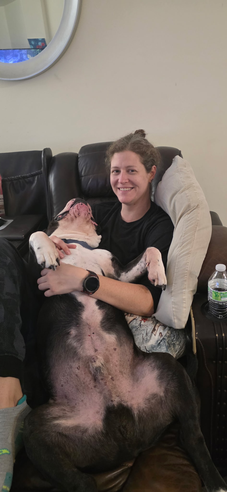 Amanda on a couch cuddling a big dog lying on its back